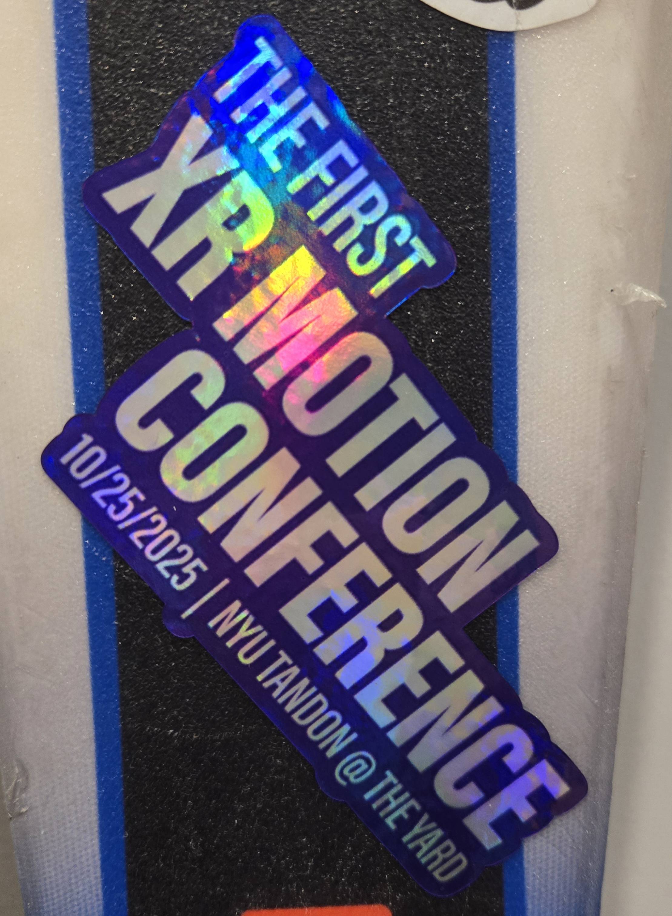 Holographic sticker reading "THE FIRST XR MOTION CONFERENCE 10/25/2025 NYU TANDON @ THE YARD"
